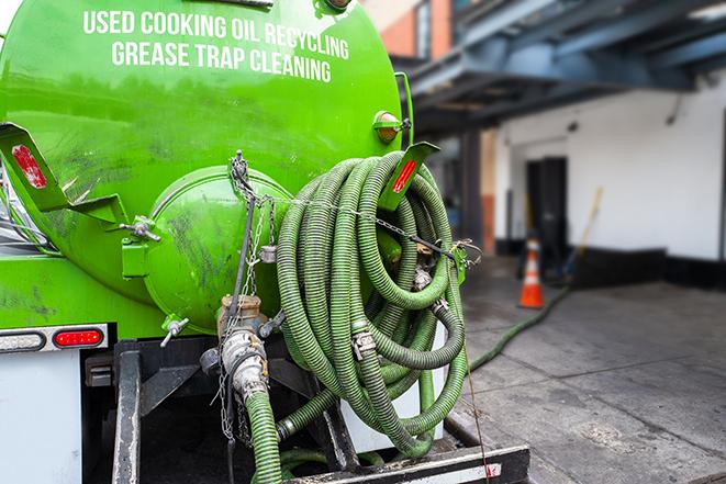 a grease trap being pumped by a sanitation technician in Arlington, NY